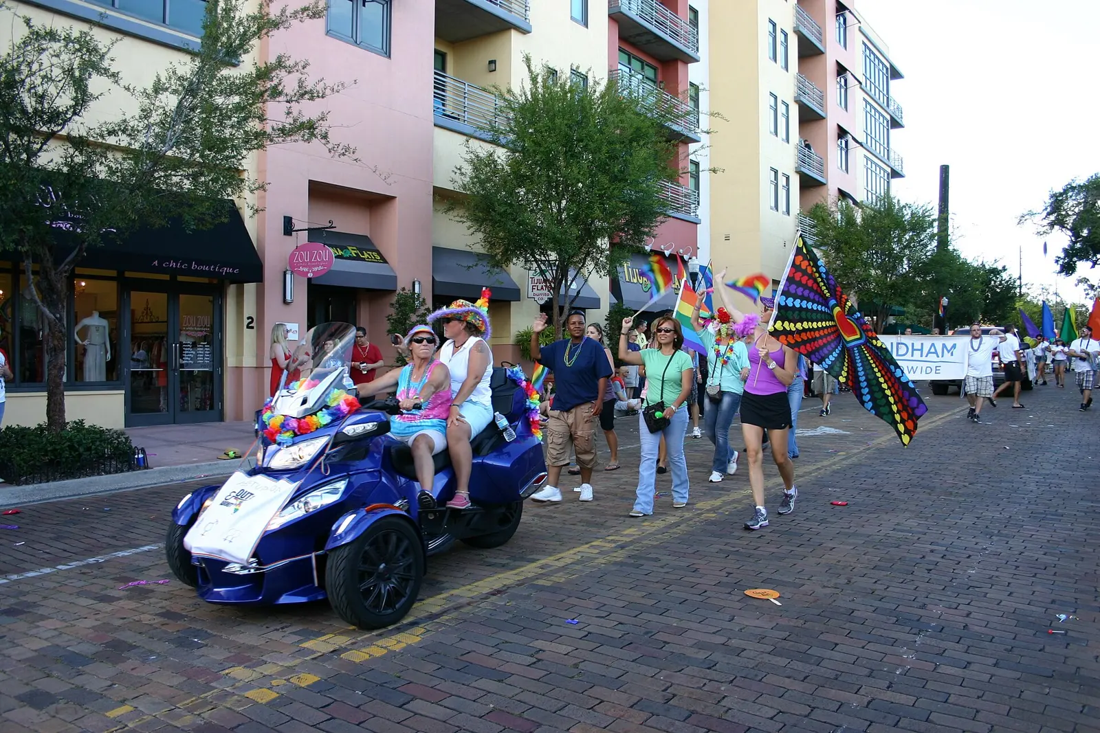 Marchers and a decorated motorcycle in the Come Out With Pride parade on a brick street in downtown Orlando