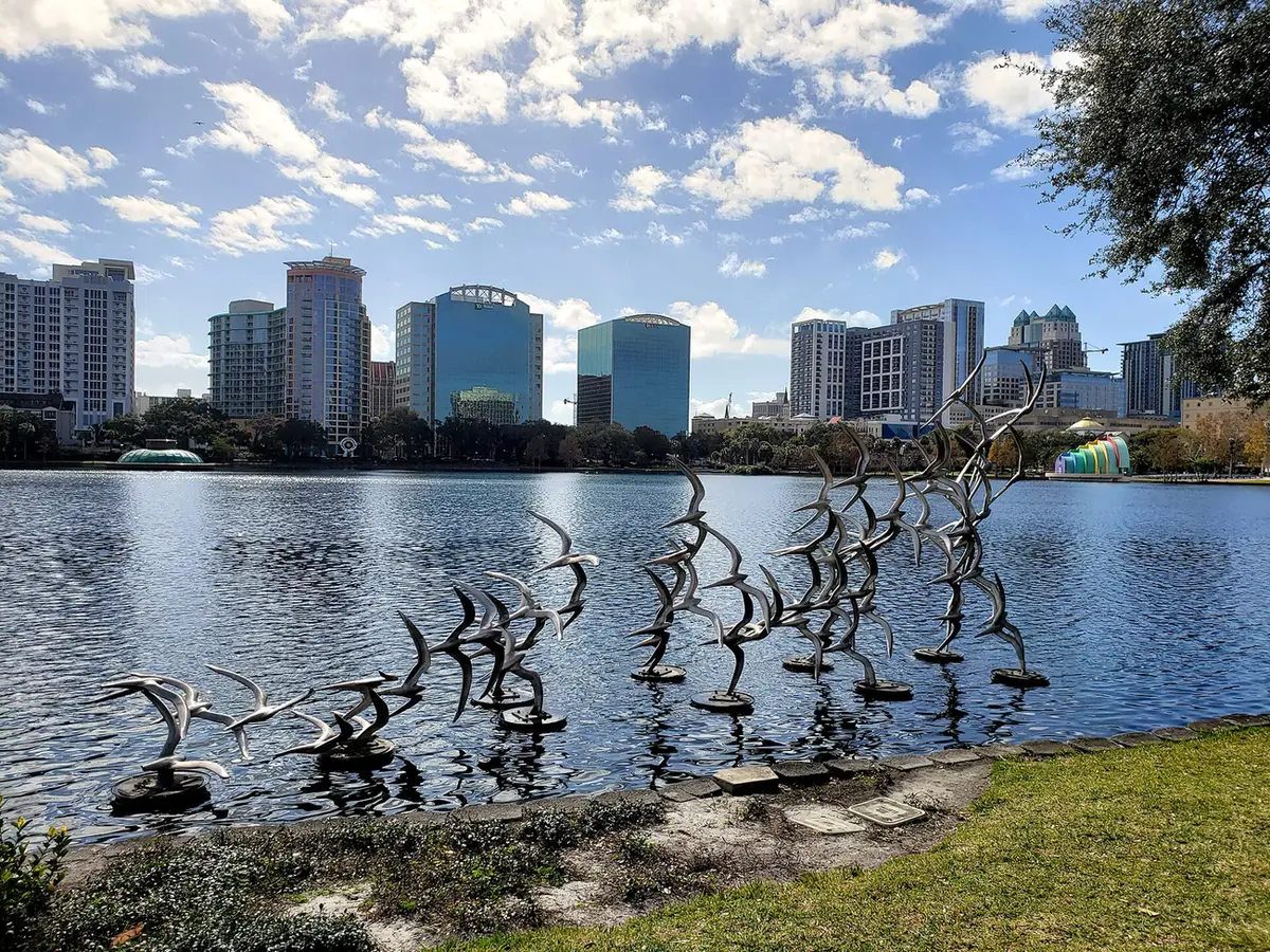 Bird sculptures on the shore of Lake Eola, with the downtown Orlando skyline behind